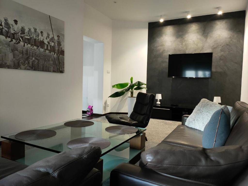 - un salon avec une table en verre et des fauteuils en cuir dans l'établissement Apartament Leonardo, à Bolesławiec