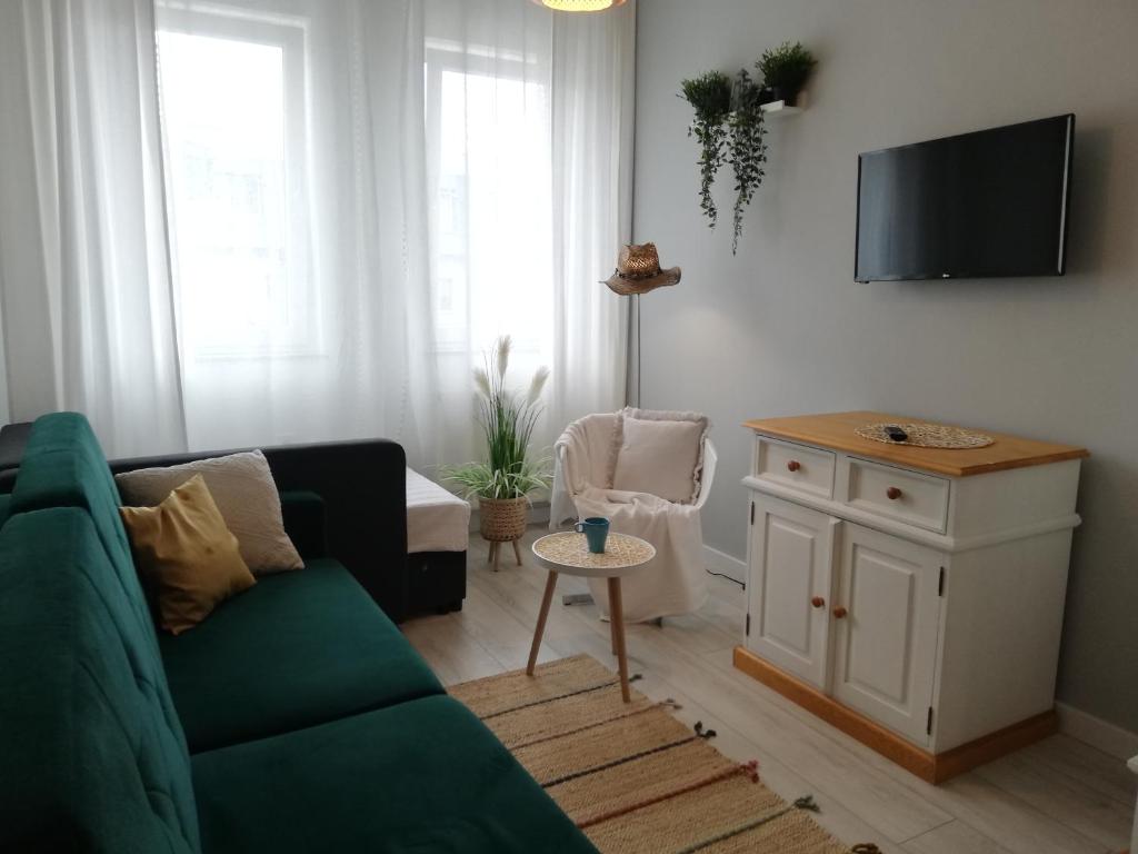 a living room with a green couch and a tv at Apartament Kapitalny in Dziwnówek