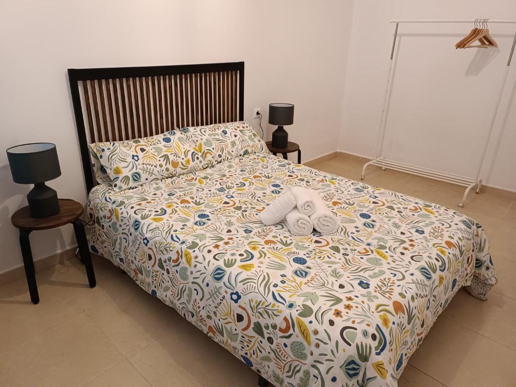 1 cama con 2 toallas y 2 lámparas. en Apartamento bajo en Mentidero, en Cádiz