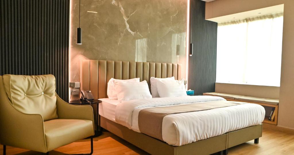 a bedroom with a large bed and a chair at Vertigo Hotel in Lagos
