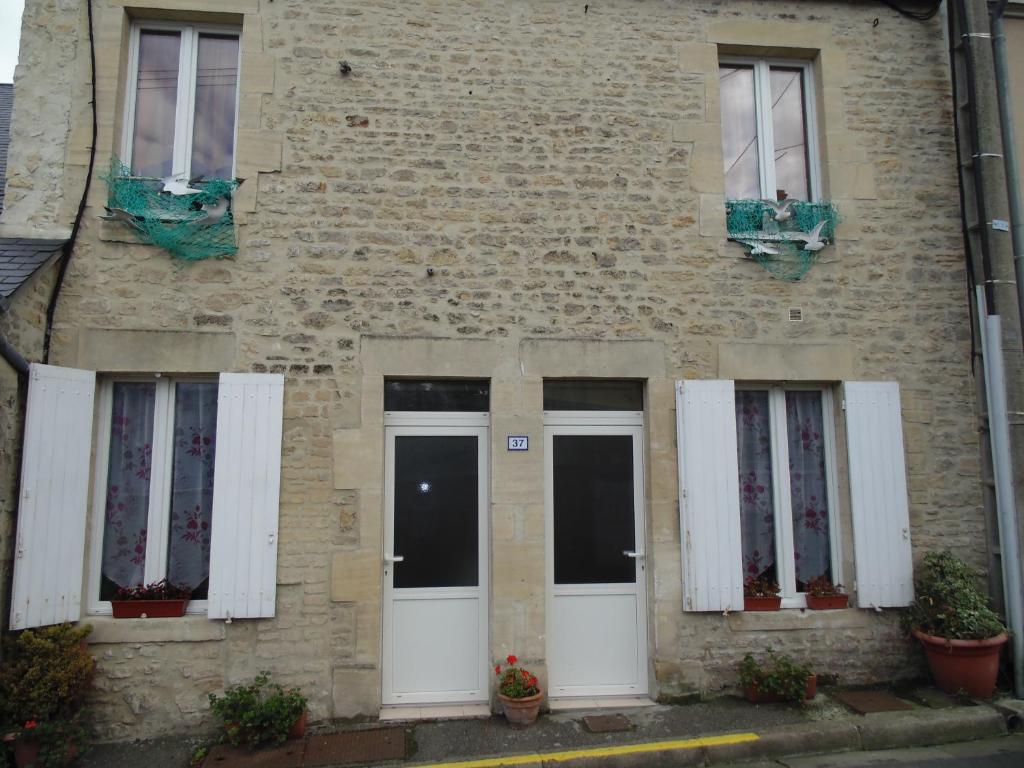 a brick building with white doors and windows at Maison en Pierre in Port-en-Bessin-Huppain