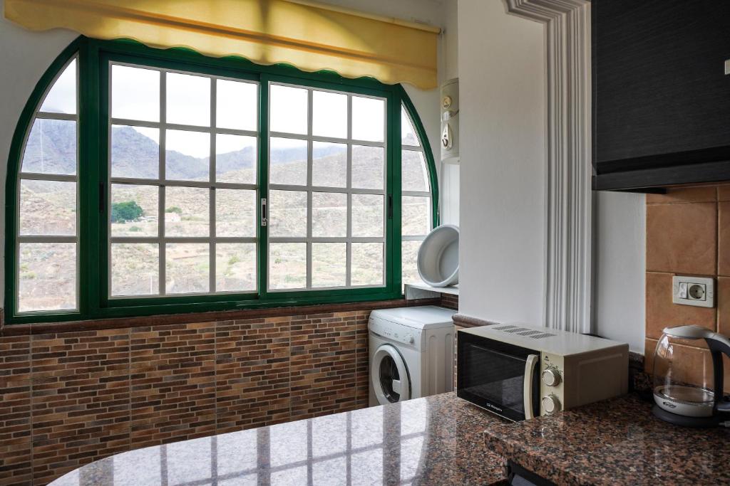 eine Küche mit einem großen Fenster und einer Mikrowelle in der Unterkunft Brisas de Anaga in Santa Cruz de Tenerife