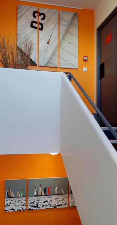 a white staircase in a room with orange walls at The Originals City, Hôtel Les Océanes, Lorient in Lorient