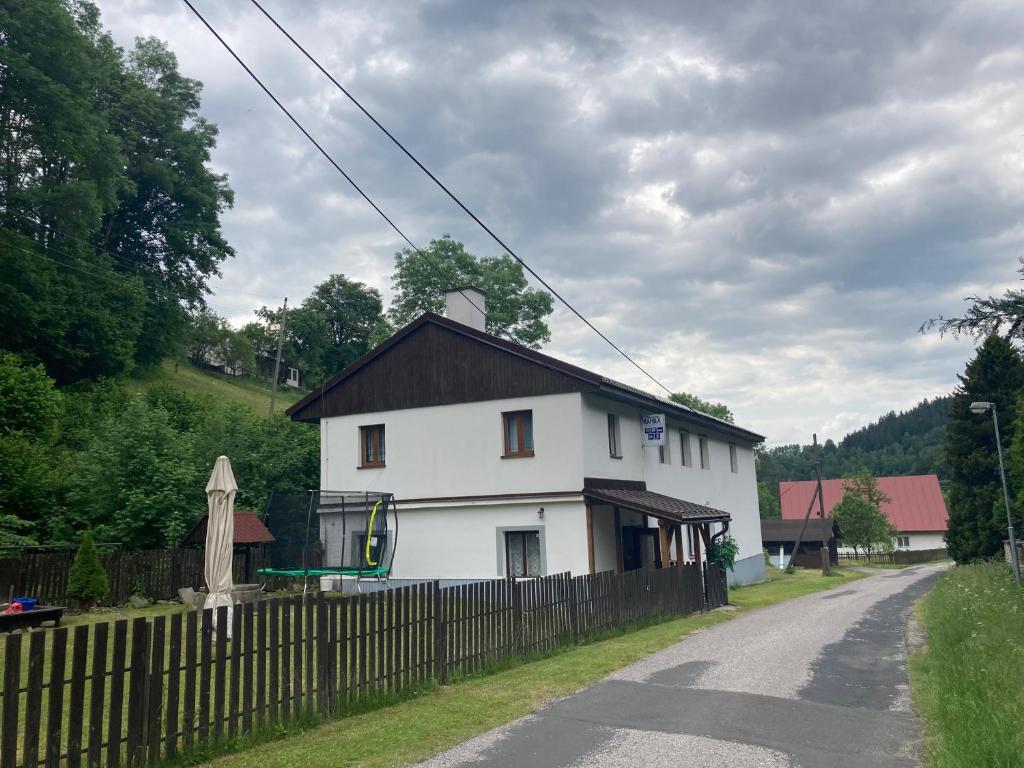 a white house with a black roof and a fence at Kamila - ubytování v Krkonoších in Dolni Dvur