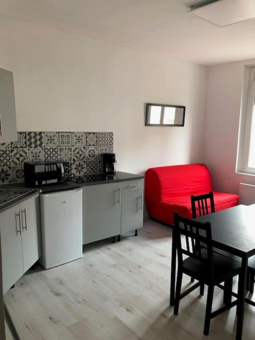 - une cuisine avec une table et un lit rouge dans une chambre dans l'établissement Studio meublé à 700 m de la plage, à Berck-sur-Mer