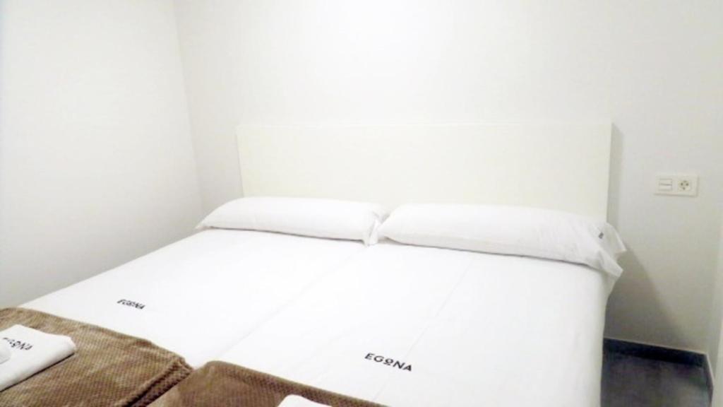 Bett in einem Zimmer mit weißer Bettwäsche und Kissen in der Unterkunft Kiriki Ideal para 2 personas, centro pueblo by Egona in Zarautz