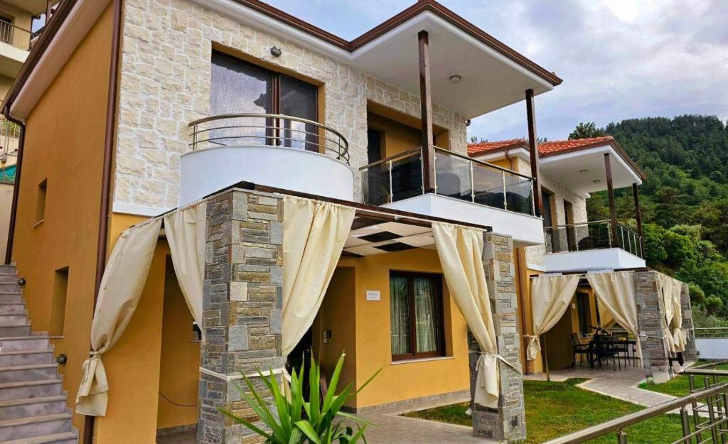 a house with a balcony with curtains on it at Seascape Villas Kinira - Elia & Anatoli in Kinira
