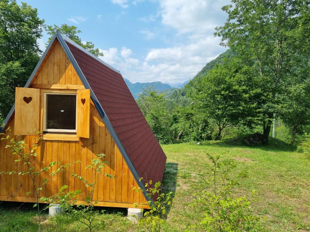 a wooden cabin with a red roof in a field at GLAMPING HOUSE ˇVITAˇ in Tolmin