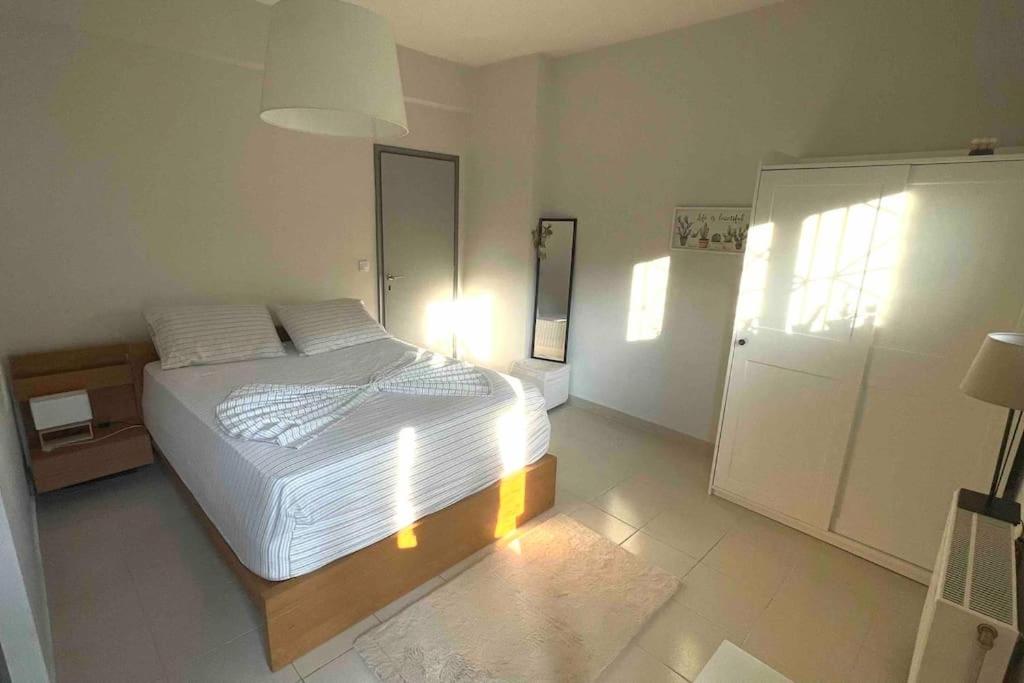 a bedroom with a white bed and a refrigerator at Summer House with Garden and Fruit Trees in Nea Makri