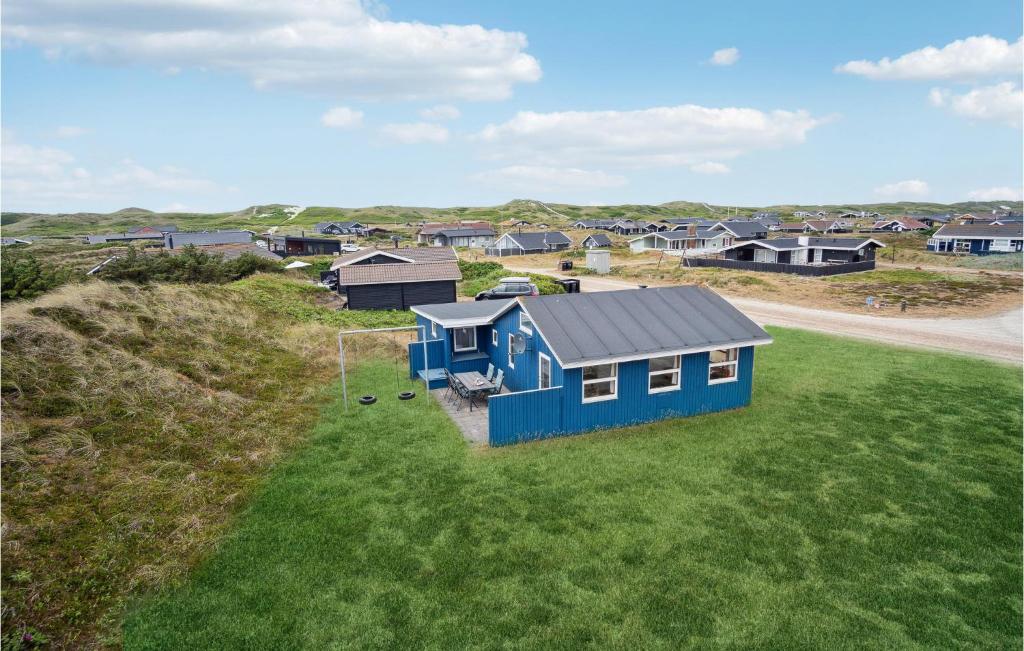 BjerregårdにあるAmazing Home In Hvide Sande With Wifiの草原の青い家屋