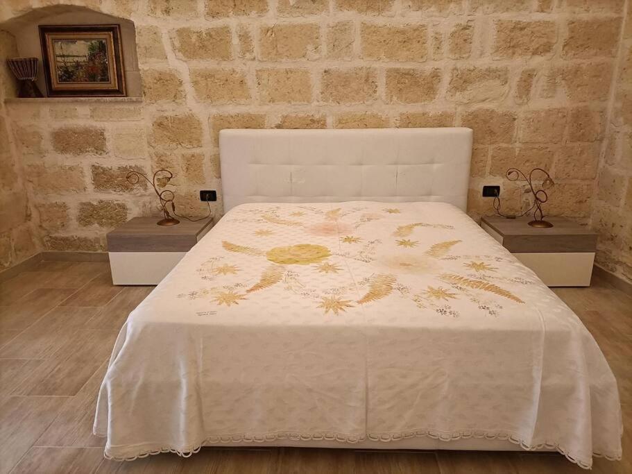 een slaapkamer met een bed met een witte sprei met bloemen bij Florooms Dimora in stile Rustico-Moderno in Corato