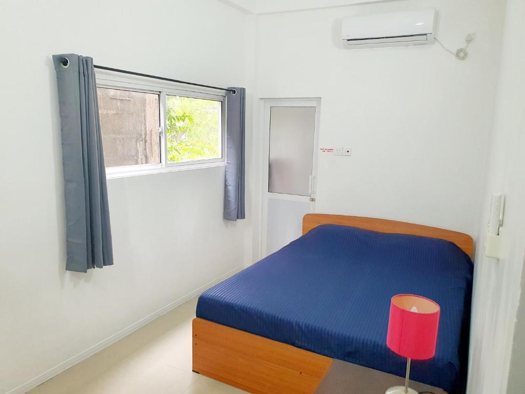 um quarto com uma cama azul e uma janela em Home From Home em Nugegoda