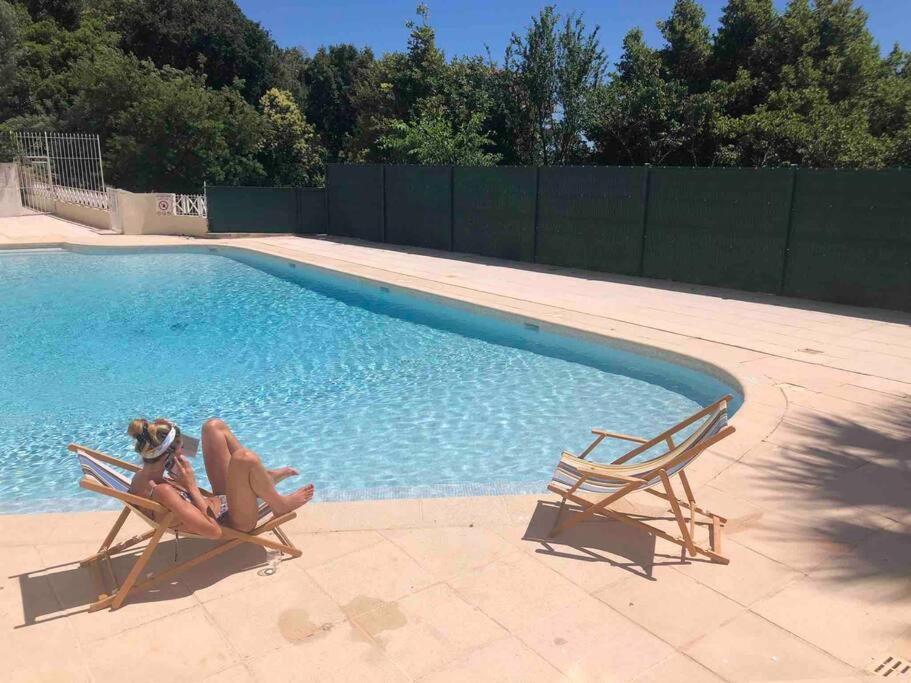 2 personnes assises dans des chaises à côté d'une piscine dans l'établissement Quiet sea view with pool, à Cannes