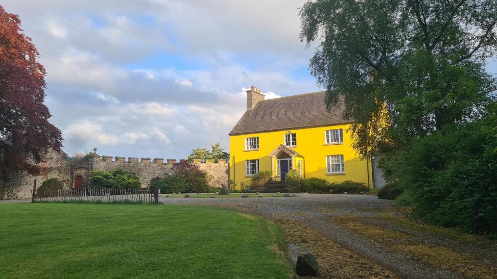 a yellow house in front of a castle at Ballylough House in Bushmills