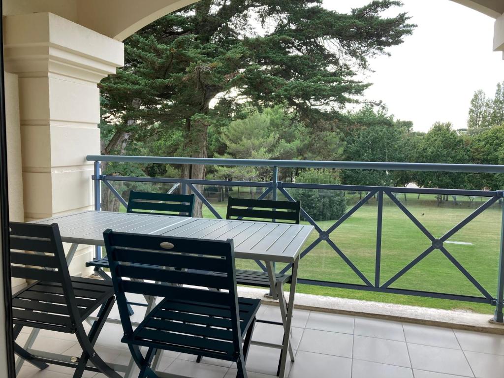 una mesa y sillas en un balcón con vistas a un campo en Studio à 300m de la plage, parc, piscine, terrasse, en La Baule
