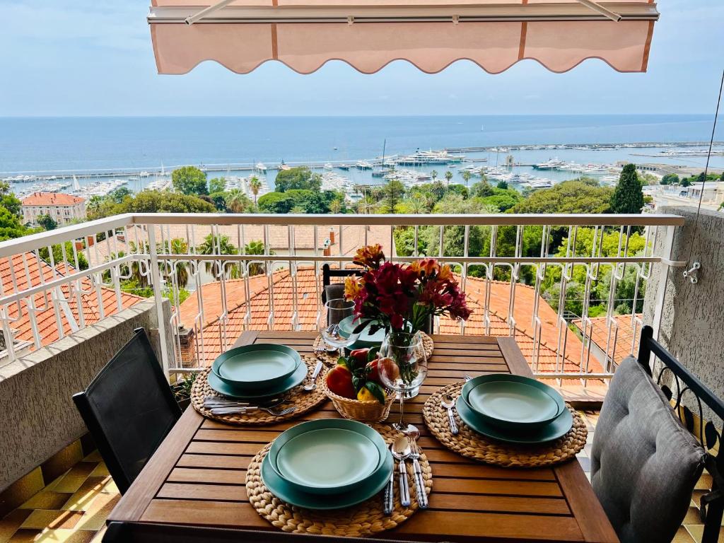 a wooden table with plates and flowers on a balcony at Special Home VISTA MARE e Parcheggio privato in Sanremo