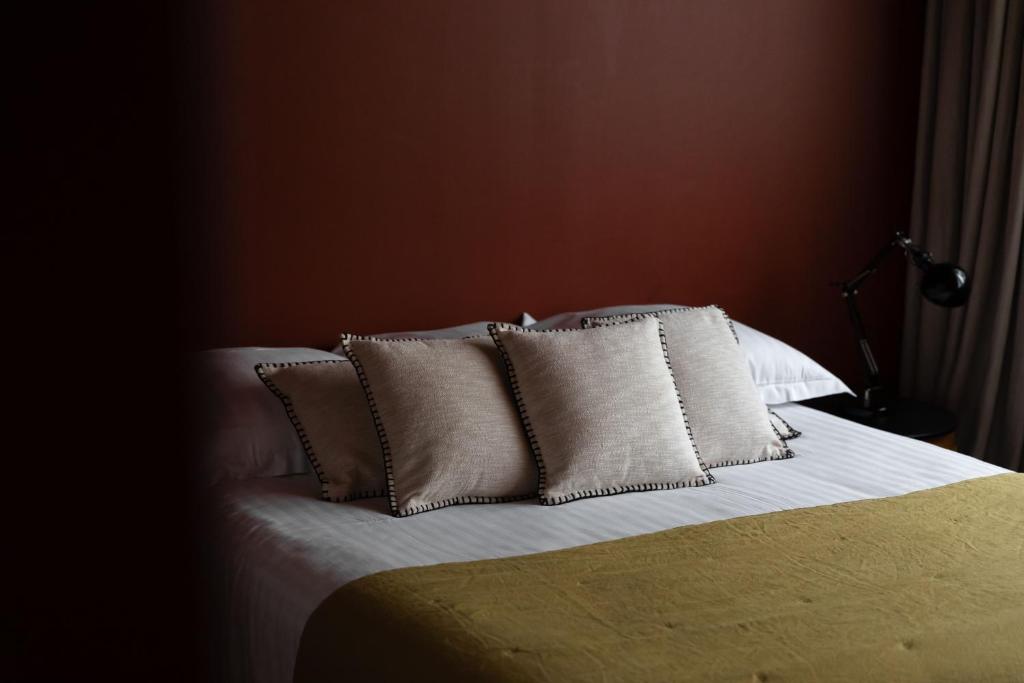 łóżko z białą pościelą i poduszkami w sypialni w obiekcie 2bis chambres d'hôtes w mieście Montreuil-sur-Mer