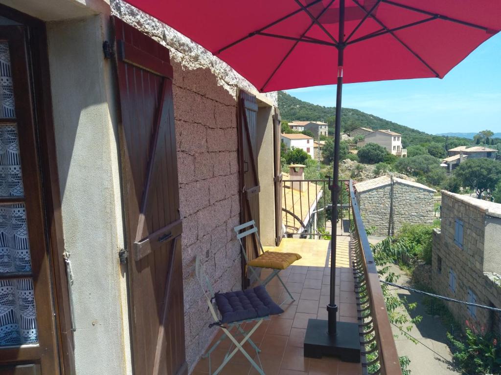 a balcony with a red umbrella and a chair at Chez Xavier in Monacia-dʼAullène