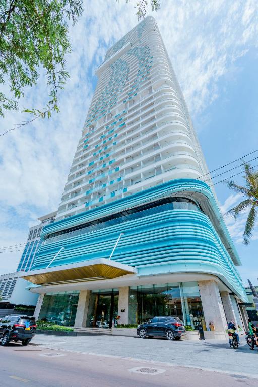 a tall building with cars parked in front of it at TYE APARTMENT - TMS Pullman Quy Nhơn in Quy Nhon