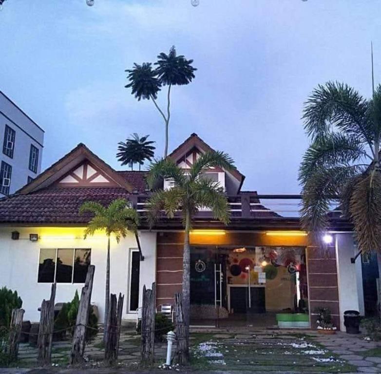 a house with palm trees in front of it at Kuu Inn Motel in Arau