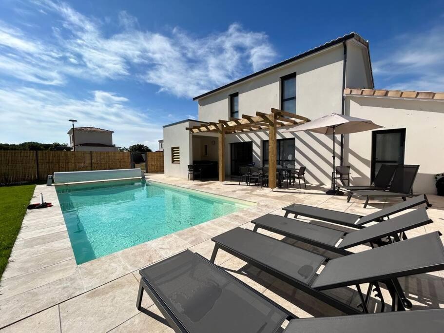 une villa avec une piscine et quelques chaises dans l'établissement La Forêt d'Armotte villa 14, à Saint-Augustin