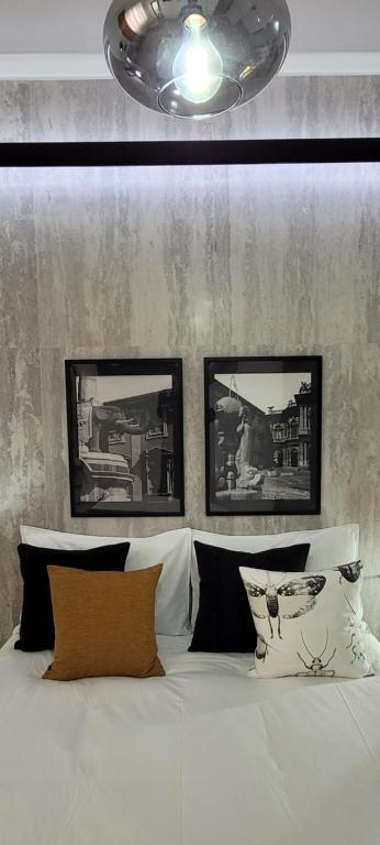 une chambre avec un lit blanc avec trois tableaux au mur dans l'établissement La dimora di Proserpina, à Catane