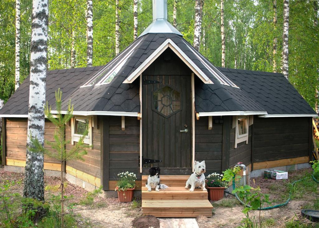 two dogs sitting on the porch of a dog house at Troll House Eco-Cottage, Nuuksio for Nature lovers, Petfriendly in Espoo