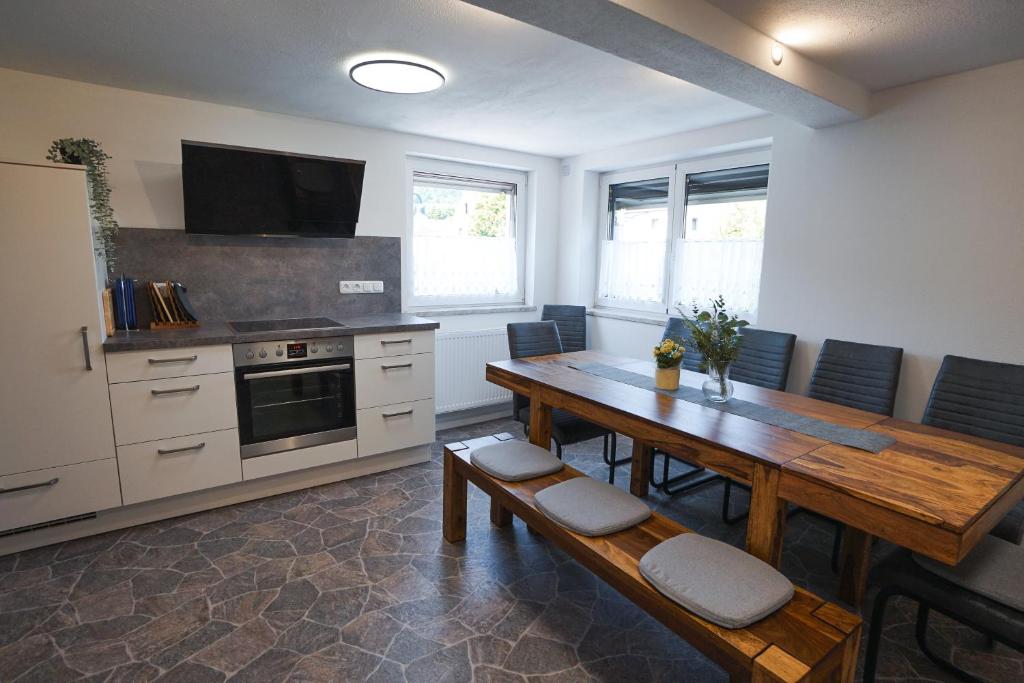 cocina con mesa de madera con sillas y barra en Rhöner Heim, en Kaltennordheim