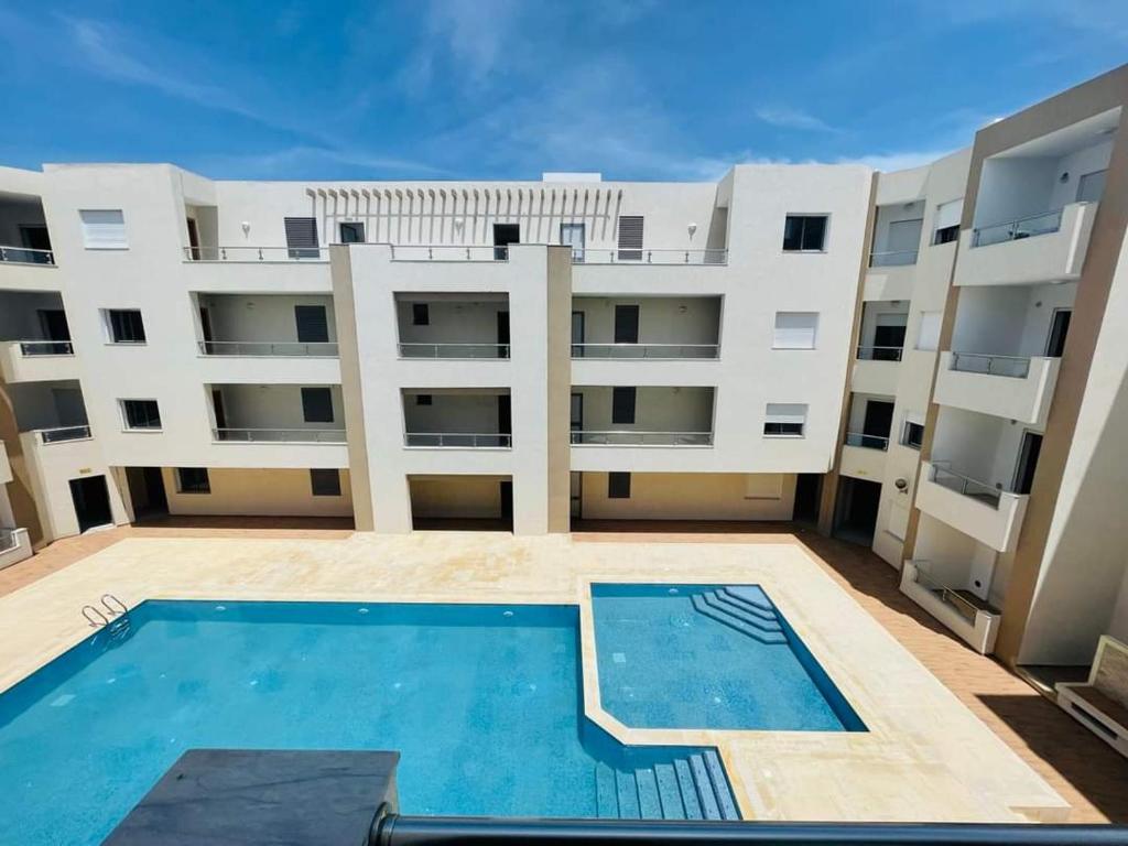 un gran edificio de apartamentos con piscina frente a él en Appartement s+1, en Kelibia