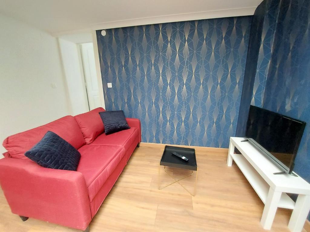 un sofá rojo en la sala de estar con TV en ° Appart 4 - Lunéville centre °, en Lunéville