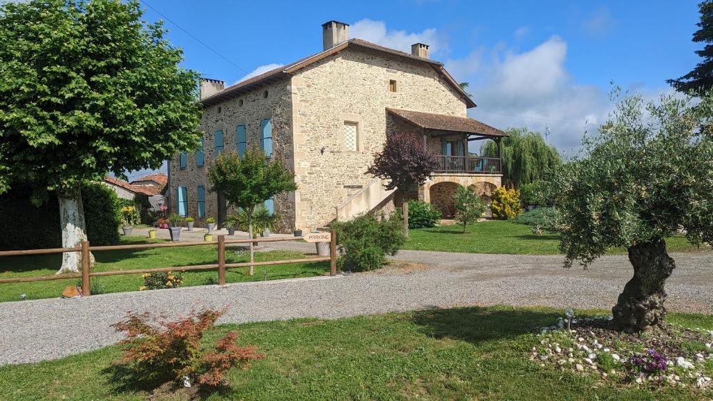 une grande maison en pierre avec un arbre en face de celle-ci dans l'établissement La Salabertie, à Bagnac