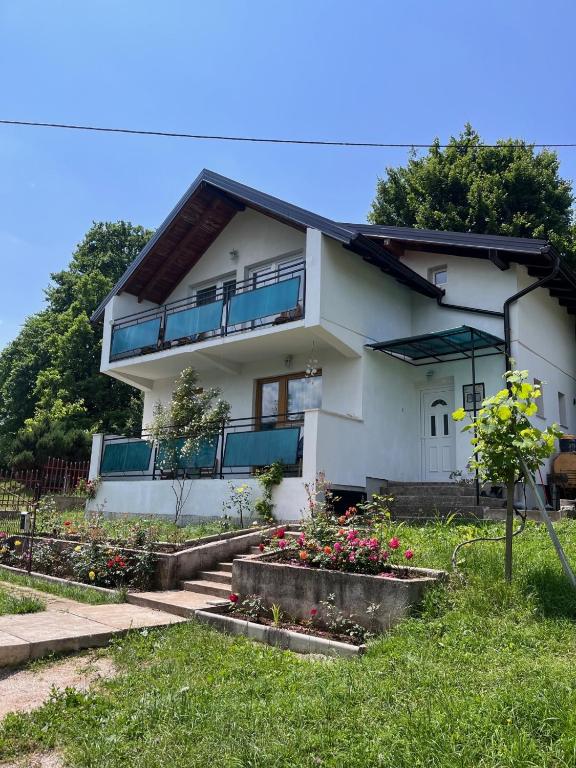 a white house with some flowers in the yard at Villa Rose in Sarajevo