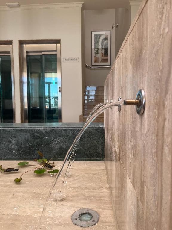 Baño con manguera de agua pegada a la pared en Hotel Santa Ana, en La Carlota