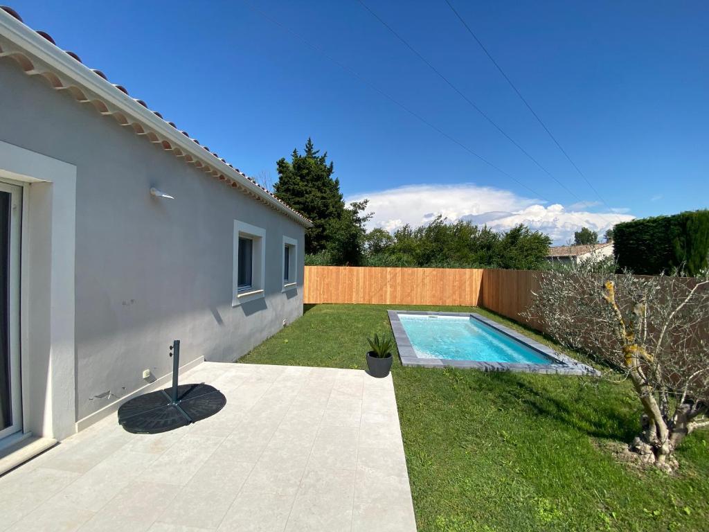 a backyard with a swimming pool next to a house at Villa 100m2 Piscine 6 personnes in Châteauneuf-de-Gadagne