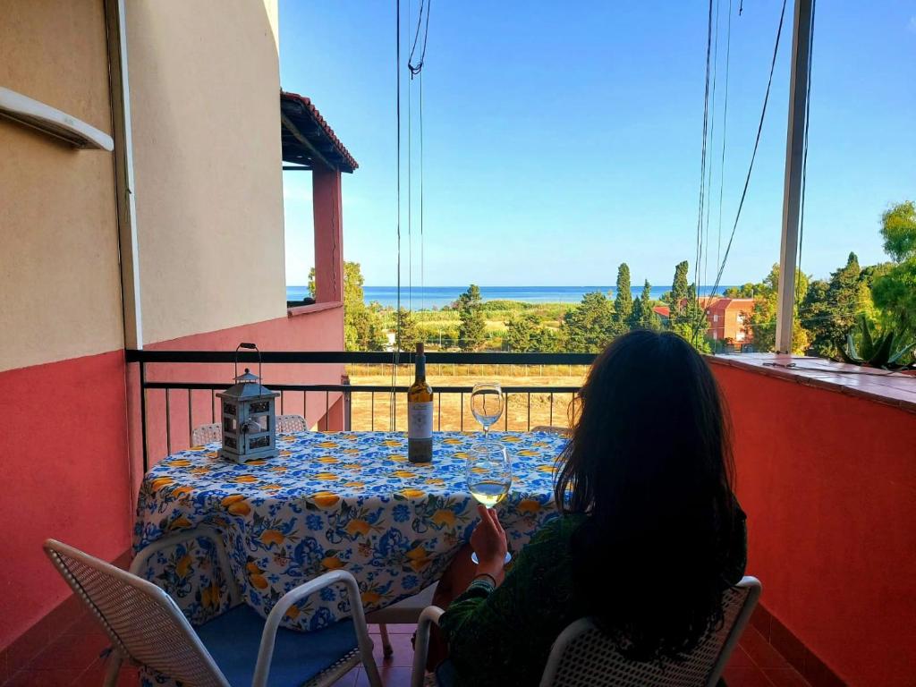 una mujer sentada en una mesa mirando por la ventana en Terrazza sul mare - a pochi minuti da Taormina, en Giardini Naxos