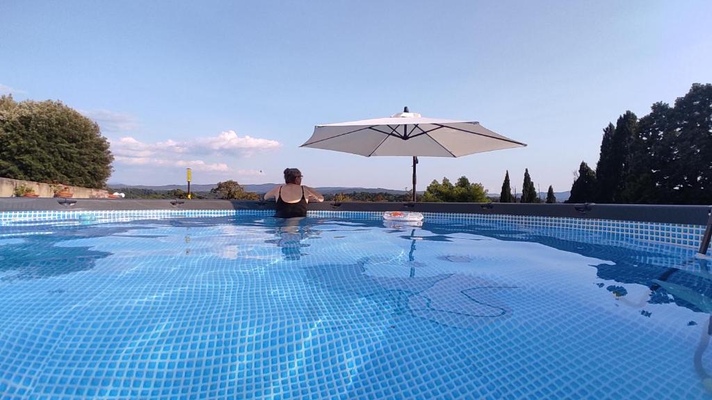 een vrouw die naast een zwembad met een parasol staat bij Villa Cicogna, Private villa with exclusive use pool in Terranuova Bracciolini