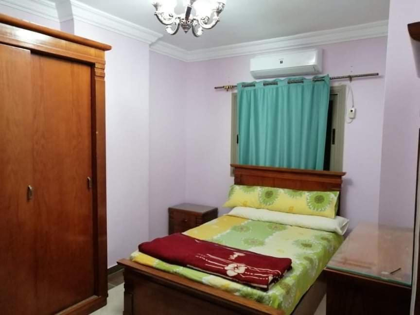 um pequeno quarto com uma cama com uma cortina verde em سيدي بشر السرايا em Alexandria