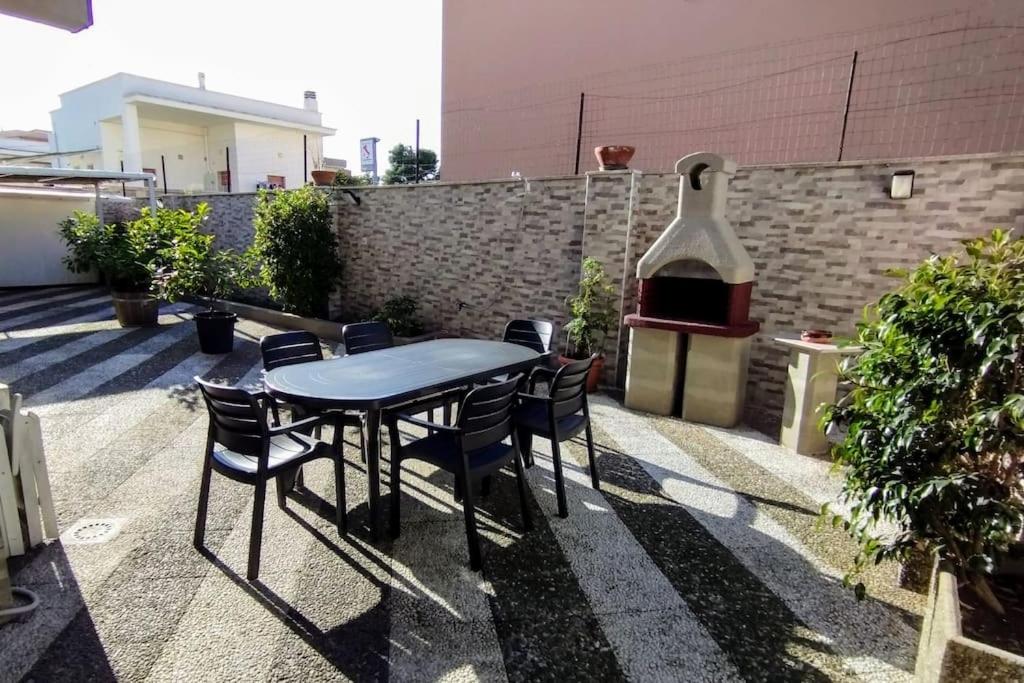 uma mesa e cadeiras num pátio com comodidades para churrascos em Grande Bilocale con giardino em Lizzano