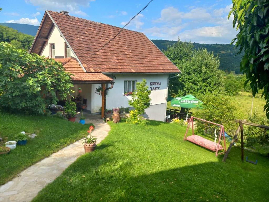 ein kleines weißes Haus mit einem Rasenhof in der Unterkunft Seosko domaćinstvo Vidović in Banja Luka