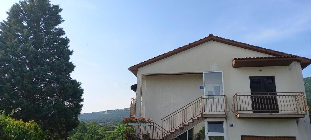 une maison blanche avec un balcon et un arbre dans l'établissement Apartman Anita, à Buzet