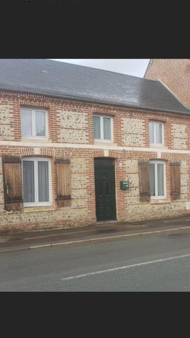 un bâtiment en briques avec une porte noire dans une rue dans l'établissement Maison de charme, à Saint-Riquier