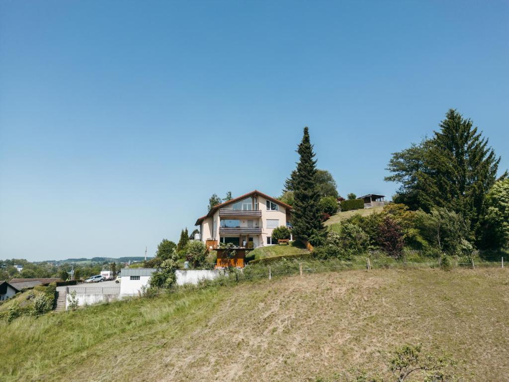 une maison assise au sommet d'une colline dans l'établissement HEIMATEL - Ferienwohnung Bergblick, à Wangen im Allgäu