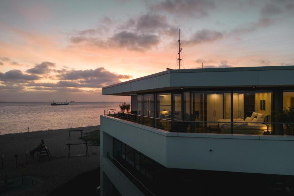 a building with a view of the ocean at sunset at Bheaven I Penthouse Premium Apartment in Bremerhaven