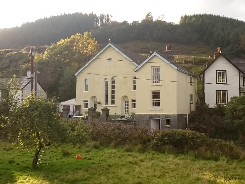 a large white house in a green field at Isfryn Cottage in Aberangell