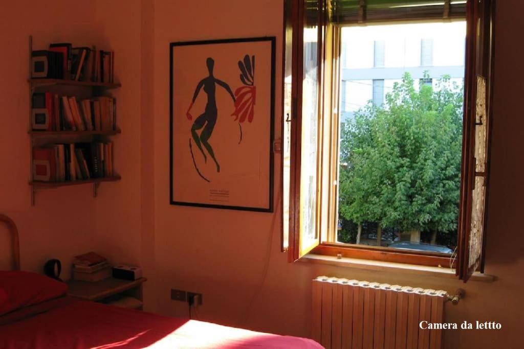 ein Schlafzimmer mit einem Bild an der Wand und einem Fenster in der Unterkunft Appartamento fronte Parco Hofer con parcheggio più bici gratuiti e check out fino ore 19 su richiesta in Mantua