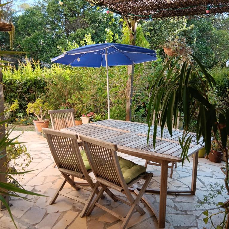 - une table en bois avec un parasol bleu sur la terrasse dans l'établissement Appartement tranquille avec jardin et piscine, à Fréjus