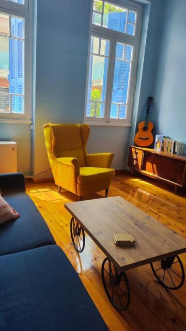 een woonkamer met een bank, een tafel en een stoel bij Yellow and blue relax house in Piraeus