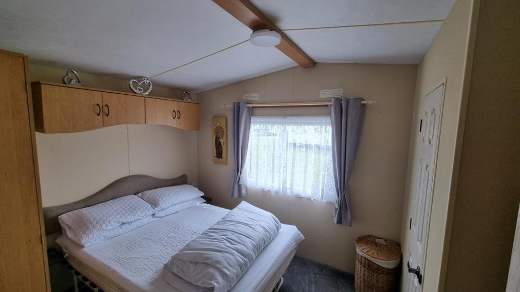 a small bedroom with a bed and a window at E16 Millfields 6 berth caravan MAX 4 ADULTS Bob family's only and lead person must be over 30 in Ingoldmells