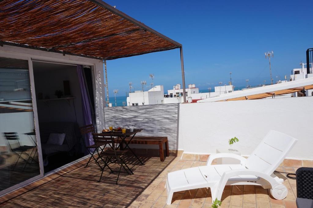 een patio met witte stoelen en een tafel op een dak bij IMPLUVIUM Conil-Terraza Privada-Parking- mayores de 25 años in Conil de la Frontera