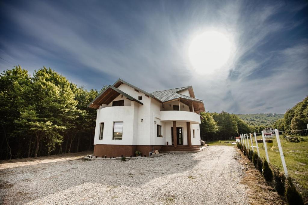 a house on a gravel road with the sun in the sky at Pensiunea Alexandra 